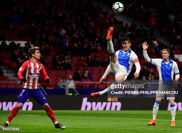 Leganes' Argentinian defender Martin Mantovani kicks the ball beside Atletico Madrid's French forward Antoine Griezmann during the Spanish league...