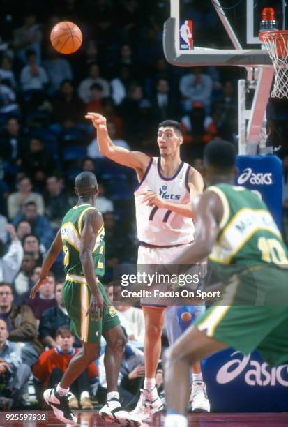Gheorghe Muresan of the Washington Bullets passes the ball over the top of Gary Payton of the Seattle Supersonics during an NBA basketball game circa...