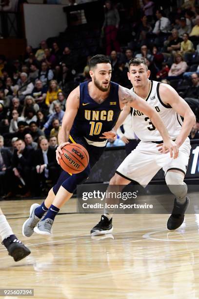 Francis Alonso guard University of North Carolina Greensboro Spartans dribbles past Fletcher Magee guard Wofford College Terriers, Tuesday, February...