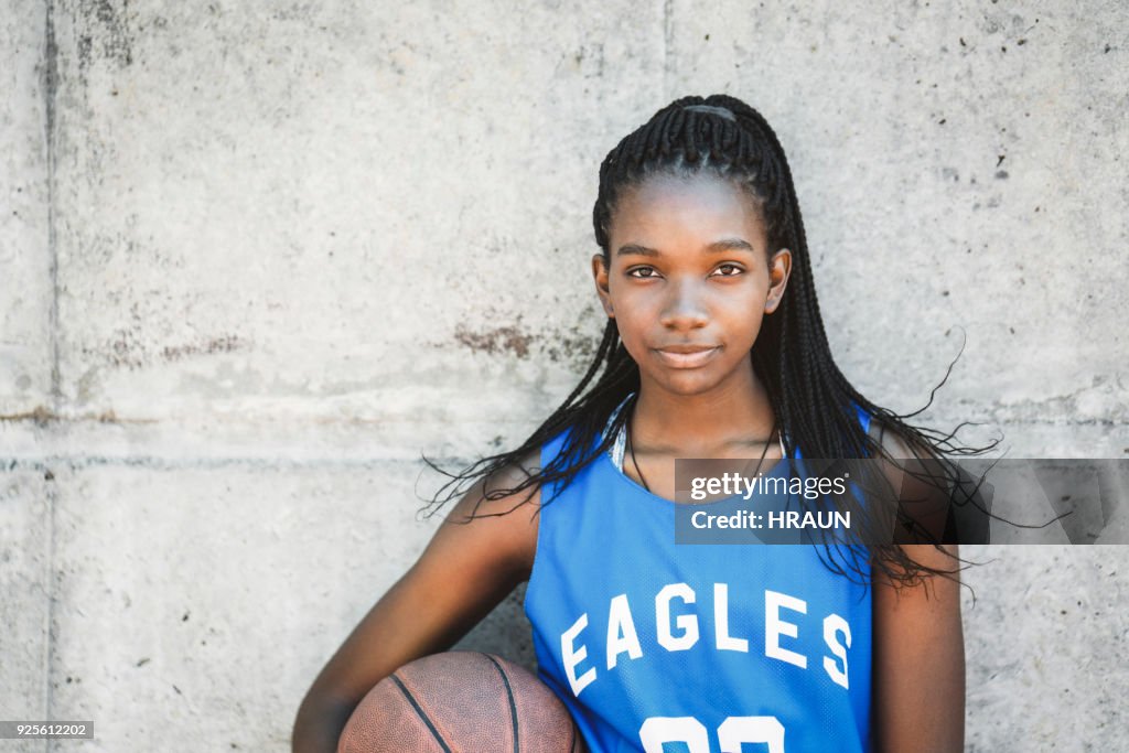 Confident female basketball player holding ball