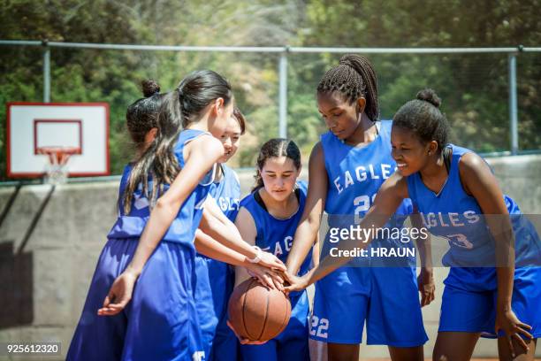 female basketball players stacking hands on ball - teenage girl basketball stock pictures, royalty-free photos & images