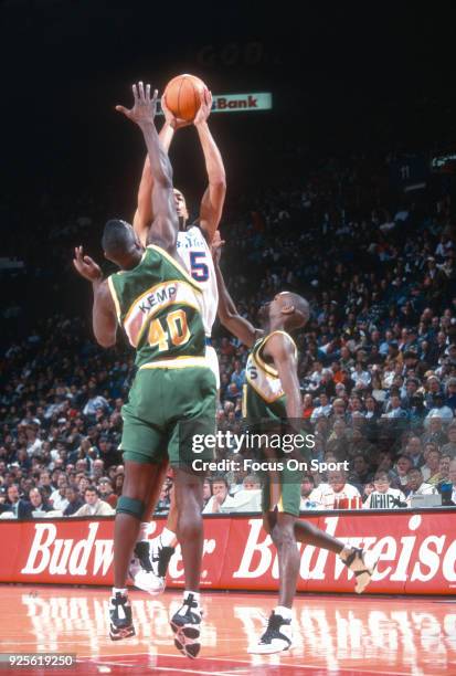 Juwan Howard of the Washington Bullets shoots over Shawn Kemp and Gary Payton of the Seattle Supersonics during an NBA basketball game circa 1995 at...