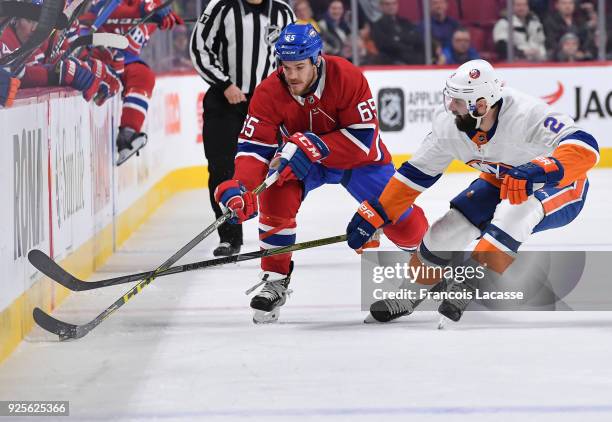 Andrew Shaw of the Montreal Canadiens passes the puck against pressure from Nick Leddy of the New York Islanders in the NHL game at the Bell Centre...