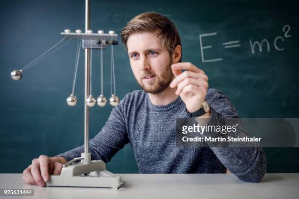 physik lehrer mit kugelstoßpendel - kugelstoßpendel stock pictures, royalty-free photos & images