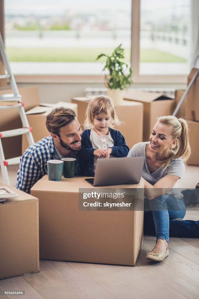 Glückliche Familie mit Laptop und entspannen Sie von ihre Sachen auspacken.