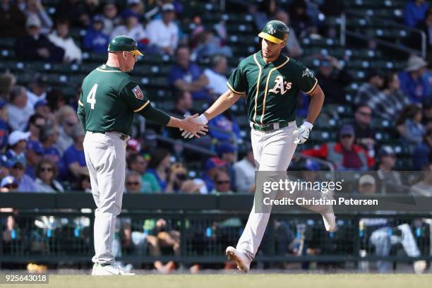 Matt Olson of the Oakland Athletics high fives third base coach Matt Williams after hitting a solo home run against the Chicago Cubs during the...