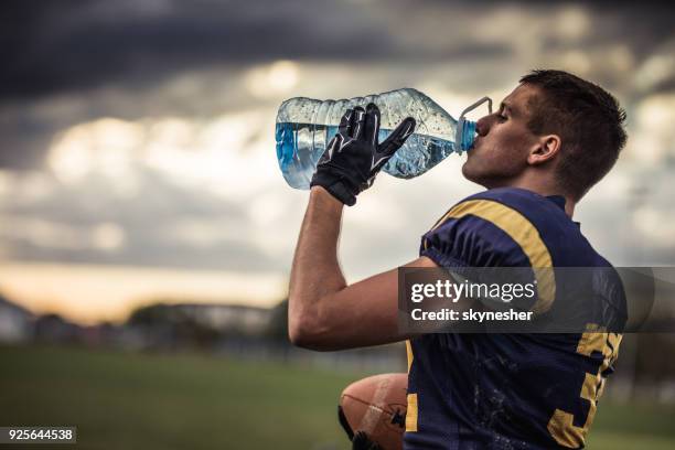 jogador de futebol americano com sede beber água fresca no campo de jogo. - sedento - fotografias e filmes do acervo