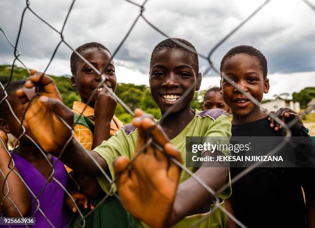 Pupils smile behind a fence near the reopened school building at Lesbury Estates in Headlands east of the capital Harare on February 1, 2018 days...