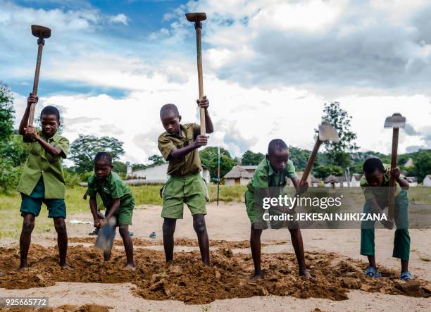 Pupils dig a longjump pit near the reopened school building at Lesbury Estates in Headlands east of the capital Harare on February 1 2018 days after...