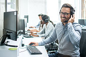 Smiling handsome customer support operator with headset working in call center.