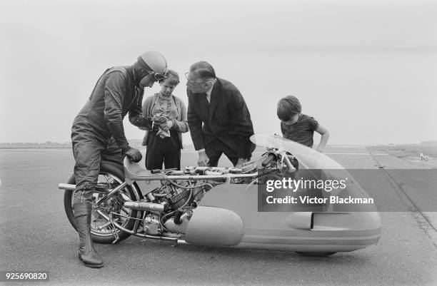 Motorcycle racer and engine tuner Freddie Cooper with his 1300cc supercharged Triumph motorcycle, his children and fuel injection expert and...