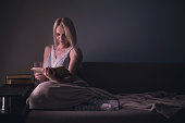 Girl enthusiastically reading a book best-selling house under a rug on a comfortable sofa with a lamp