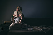 Girl enthusiastically reading a book best-selling house under a rug on a comfortable sofa with a lamp