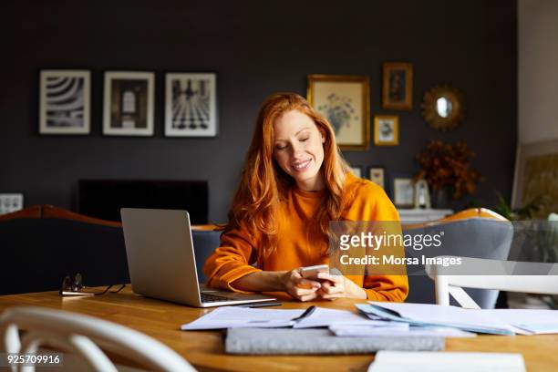 smiling businesswoman using mobile phone at home - freelance work stock pictures, royalty-free photos & images