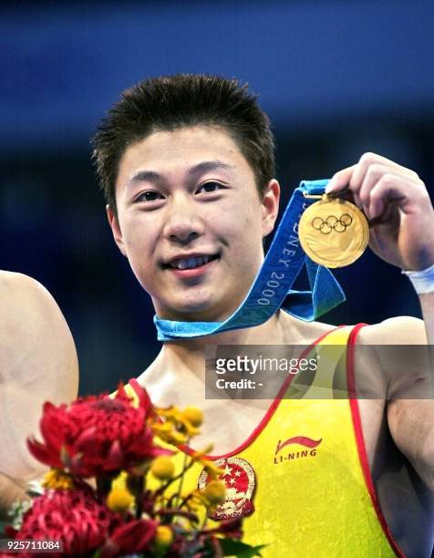 Gold medal winner Li Xiaopeng of China holds his medal, 25 September 2000, following the men's apparatus finals on the parallel bars at the Sydney...