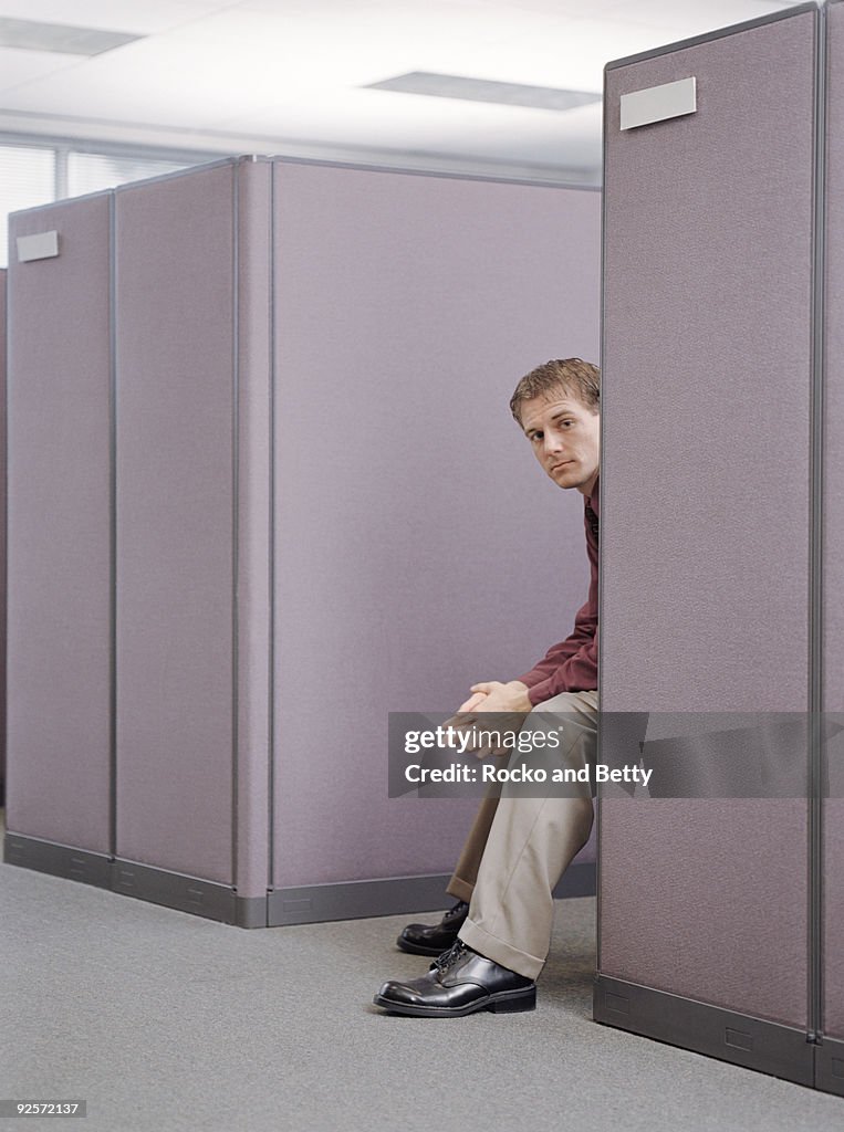 Man peeking from behind a cubicle