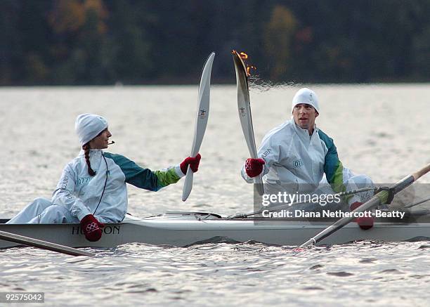 Member of the Canadian men's eights lights the flame of the coxswain from the junior eights during the Olympic Torch relay in Saanich, Canada October...