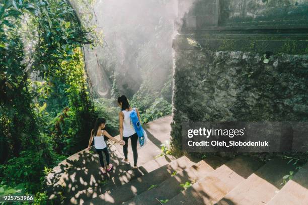 Mother and daughter walking in tropical park after yoga session