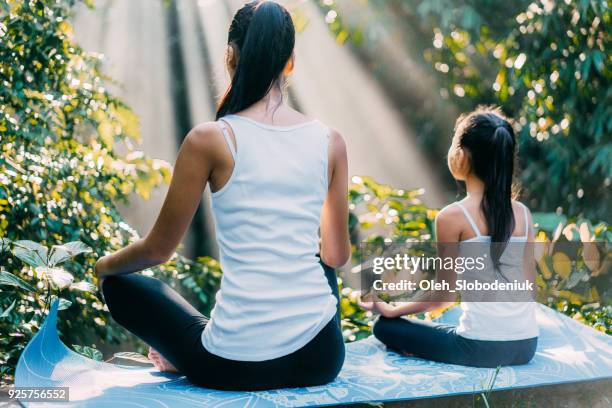 mother and daughter meditating in lotus position in rainforest in bali - posture stock pictures, royalty-free photos & images