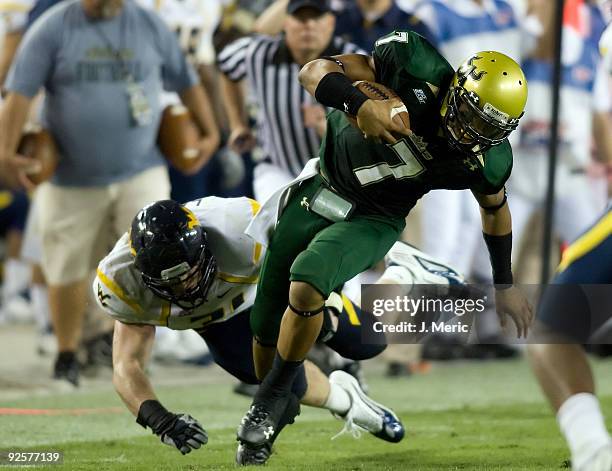 Quarterback B.J. Daniels of the South Florida Bulls runs out of the grasp of defender Pat Lazear of the West Virginia Mountaineers during the game at...