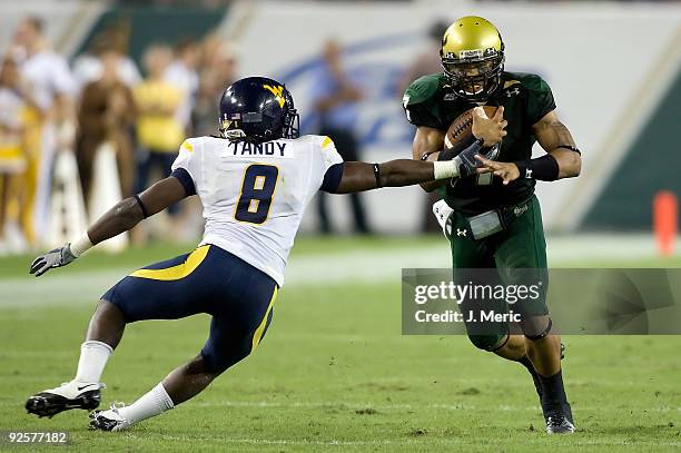 Quarterback B.J. Daniels of the South Florida Bulls runs out of the grasp of defender Keith Tandy of the West Virginia Mountaineers during the game...