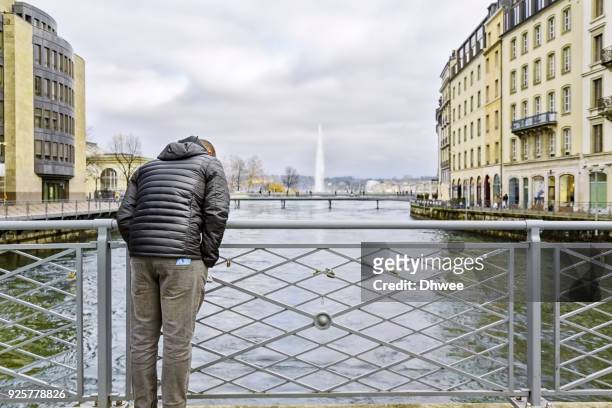 tourist standing against fence looking down the lake geneva - looking over fence stock pictures, royalty-free photos & images