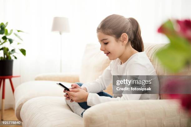 little girl having fun with smart phone at home - online predator stock pictures, royalty-free photos & images