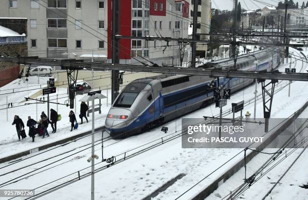 Passengers walk out a TGV train blocked by snow on March 1, 2018 in Montpellier in the south of France. / AFP PHOTO / PASCAL GUYOT