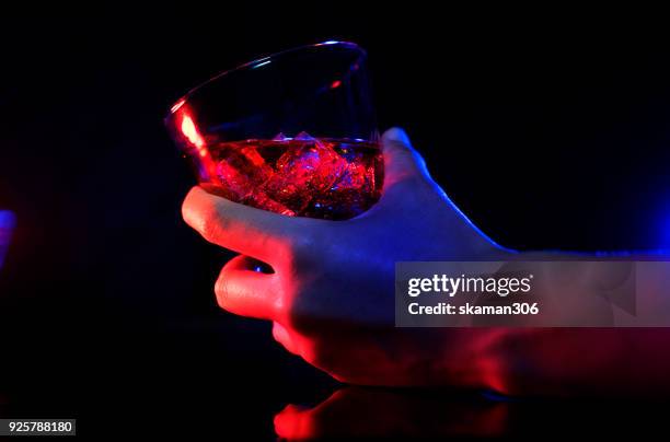hand holding glass of whiskey - alcolismo foto e immagini stock