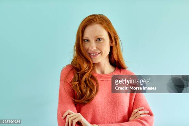 smiling woman standing against blue background - living coral stock pictures, royalty-free photos & images