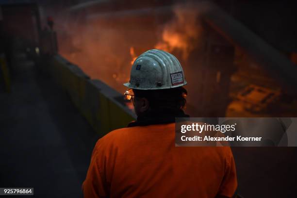 An employee works in front of the blast furnace past rolls of sheet steel at a mill of German steel producer Salzgitter AG on March 1, 2018 in...