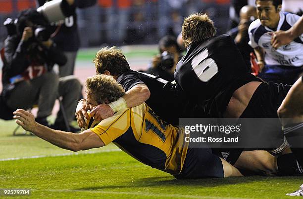 Peter Hynes of the Wallabies dives over to score a try in the tackle of Jimmy Cowan and Adam Thomson of the All Blacks during the 2009 Bledisloe Cup...