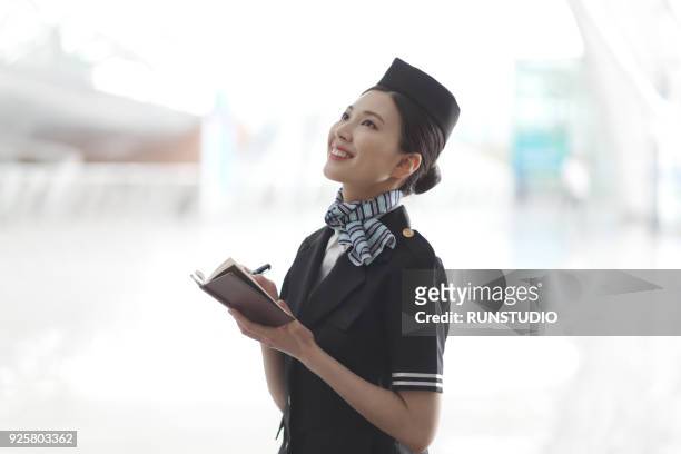 flight attendant taking note in airport - airhostess stock pictures, royalty-free photos & images