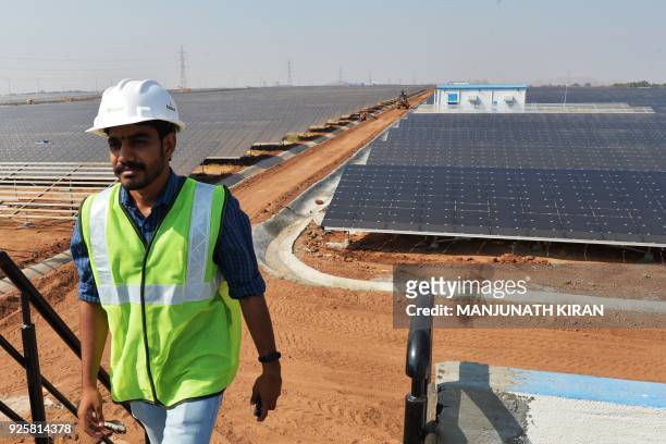 An Indian worker conducts routine checks of solar panels at "Shakti Sthala", the 2000 Megawatt solar power park in Pavagada Taluk, situated about 150...