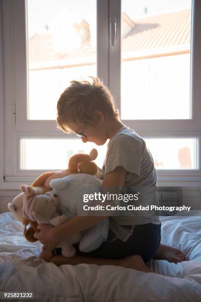 young boy hugging teddy bears at home - personas ciudad stock pictures, royalty-free photos & images