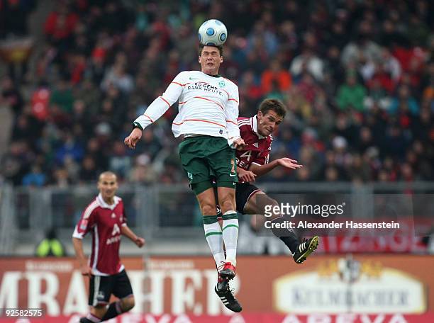Christian Eigler of Nuernberg jumps for a header with Sebastian Boenisch of Bremen during the Bundesliga match bewteen 1.FC Nuernberg and Werder...