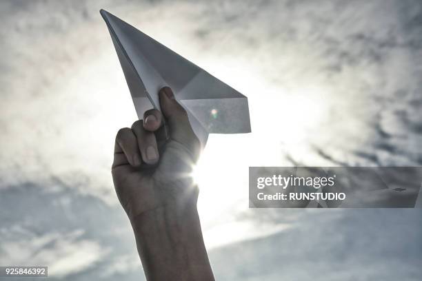 woman holding paper plane toward sky - sky from plane stock-fotos und bilder