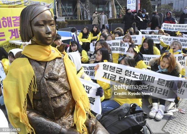 People protest in front of the Japanese Embassy in Seoul on March 1 near a statue symbolizing "comfort women" forced to work in Japanese wartime...