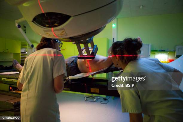 Radiotherapy unit of hospital, Savoie, France, Two technicians set up a patient for a radiotherapy session to treat breast cancer. An electron...