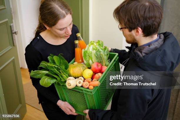 Berlin, Germany Posed Scene: A vegetable box scheme with fresh organic fruit and vegetables is handed over at the front door by a supplier to a...