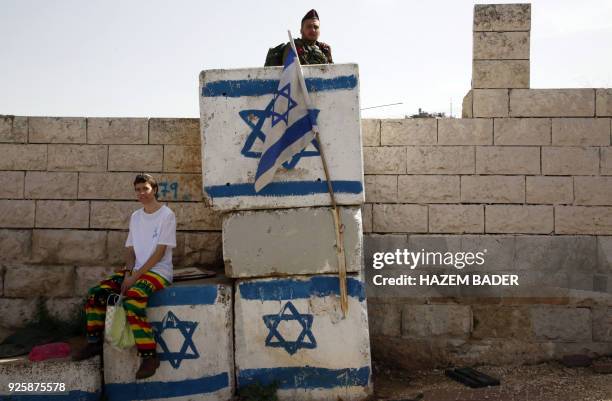 In Israeli soldier keeps watch as Israeli settlers celebrate the Jewish Purim holiday at al-Shuhada street in the West Bank town of Hebron, on March...
