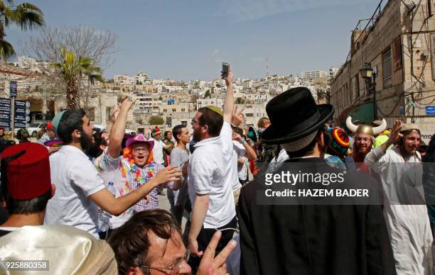 Israeli settlers celebrate the Jewish Purim holiday at al-Shuhada street in the divided West Bank town of Hebron, on March 01, 2018. The...