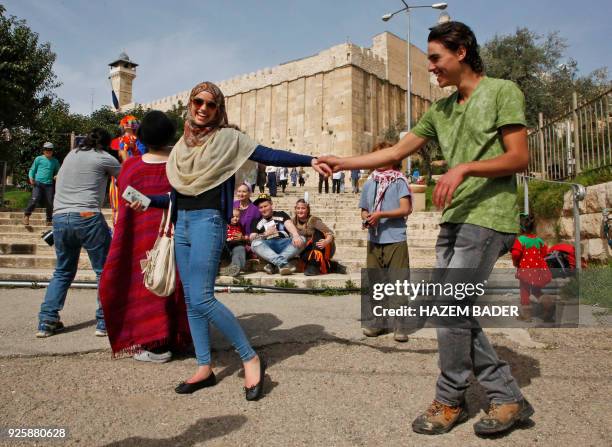 Israeli settlers celebrate the Jewish Purim holiday in front of Ibrahimi Mosque at al-Shuhada street in the divided West Bank town of Hebron, on...