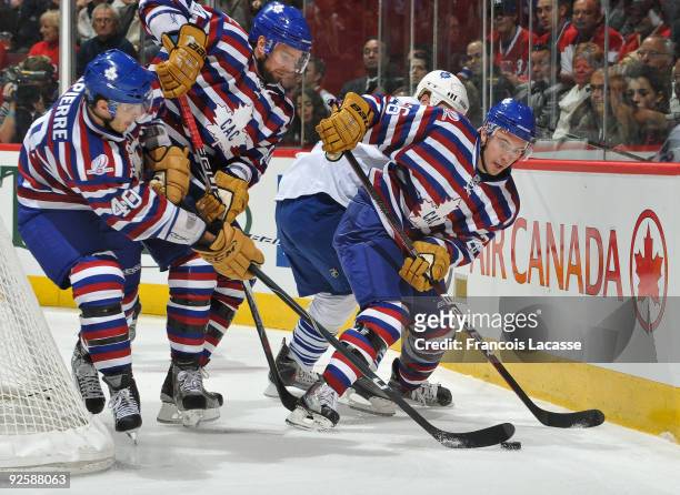 Josh Gorges of the Montreal Canadiens and teammates Guillaume Latendresse and Maxim Lapierre battle for the puck during the NHL game against the...