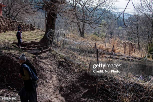 Kashmiri men walk in front the bunker of Indian army as they walk towards their abandoned home during a fresh skirmish along the border on February...