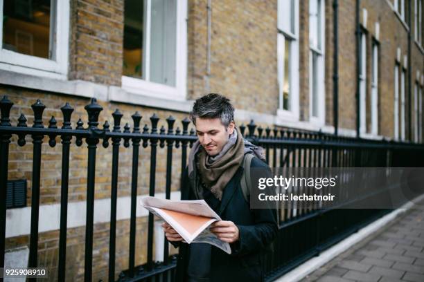 Young man reading newspapers in London downtown