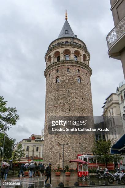 Photograph of the Galata Tower, with pedestrians visible in the foreground, Istanbul, Turkey, November 20, 2017.
