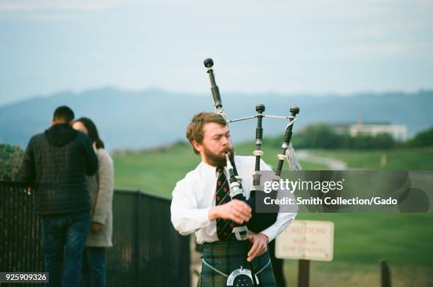 Bagpiper in classic Scottish kilt and costume playing at sunset at the Ritz Carlton Half Moon Bay luxury hotel in Half Moon Bay, California, December...
