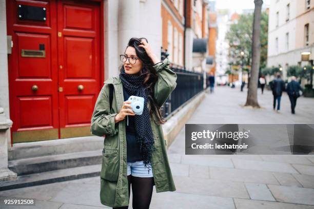 Young tourist woman standing on the streets of London holding her vintage film camera