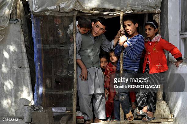 Fiteen year old Afghan Enayat stands with other children in a tiny workshop where he together with other minors weave carpets in Char Qala District...